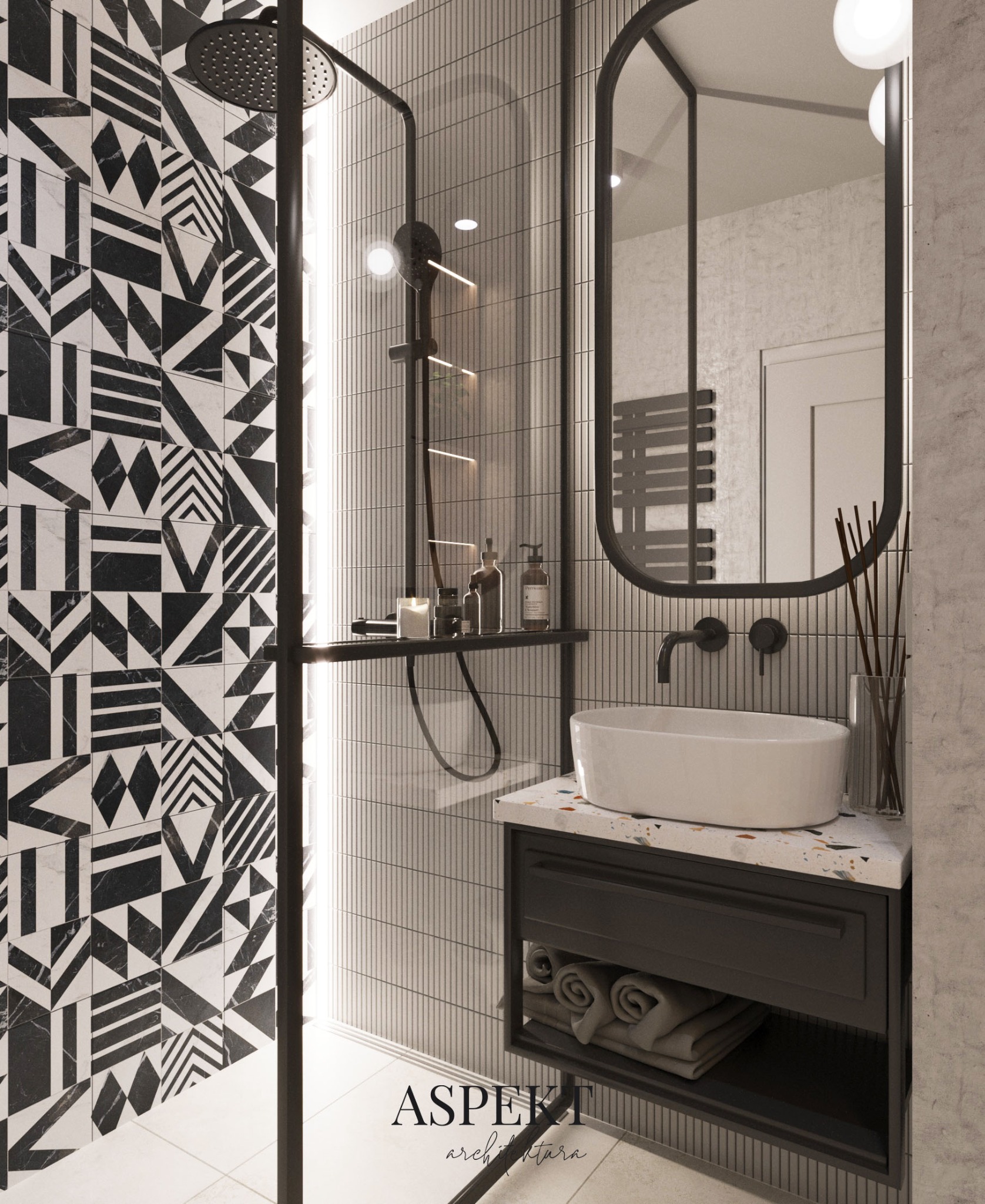 Nowoczesna łazienka z kabiną prysznicową, czarno-białymi wzorzystymi płytkami, umywalką nablatową na szafce z blatem lastryko i okrągłym lustrem w czarnej ramie.
