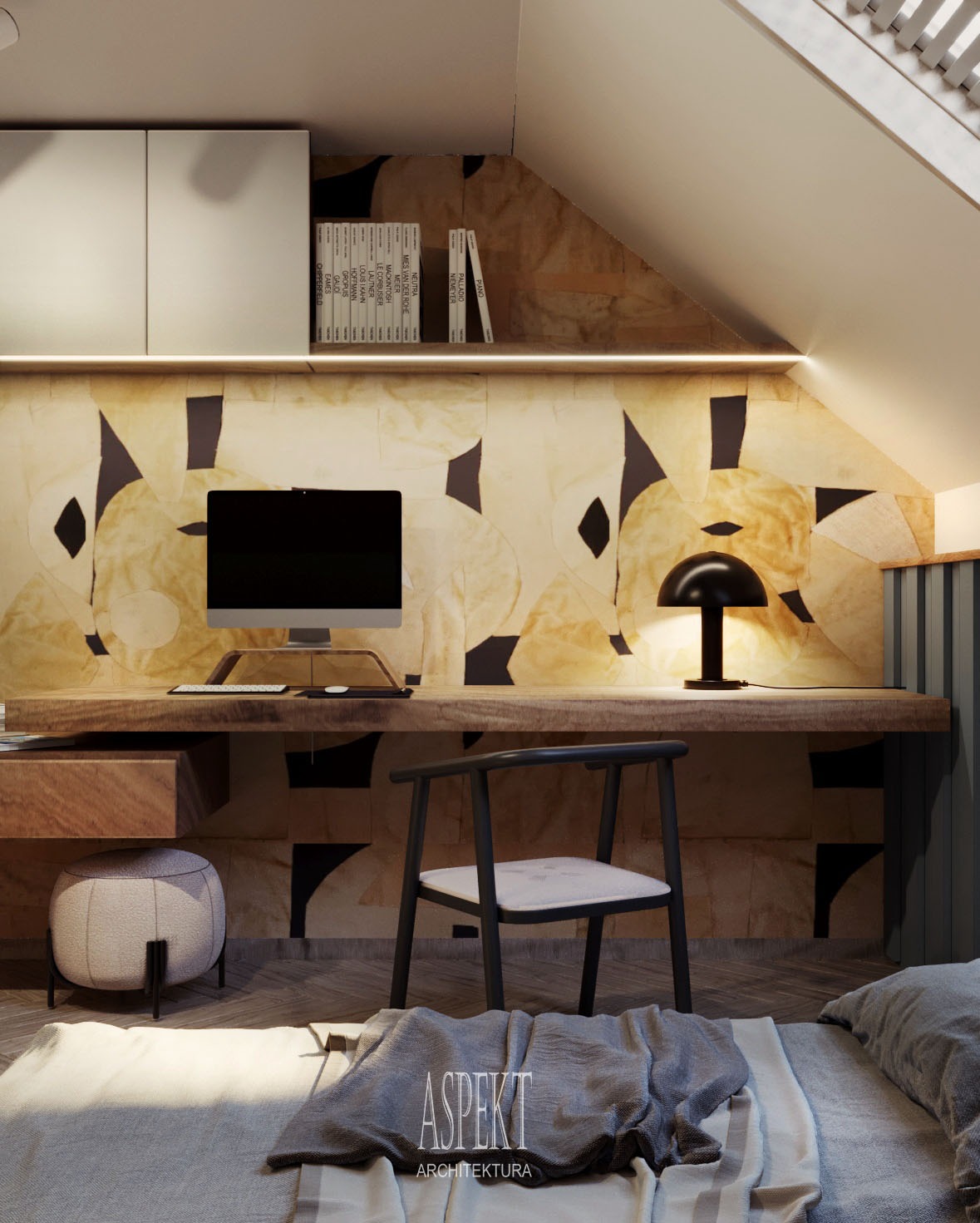 Biurko z blatem z litego drewna w pokoju na poddaszu, z komputerem, lampką i książkami na tle ściany z abstrakcyjnym wzorem, widoczne łóżko z szarą narzutą z logo firmy projektowej.