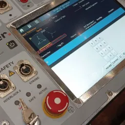 Panel sterowania urządzenia pomiarowego z ekranem dotykowym prezentującym dane o rezystancji uzwojenia transformatora, widoczne gniazda pomiarowe, przycisk bezpieczeństwa i kluczyk interlock