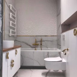LiKo KOSTIANTYN ZHURYHORA - Nowoczesna łazienka z białymi marmurkowymi płytkami, złotymi akcentami, podwieszaną toaletą i grzejnikiem drabinkowym, prezentująca eleganckie wykończenie wnętrza.