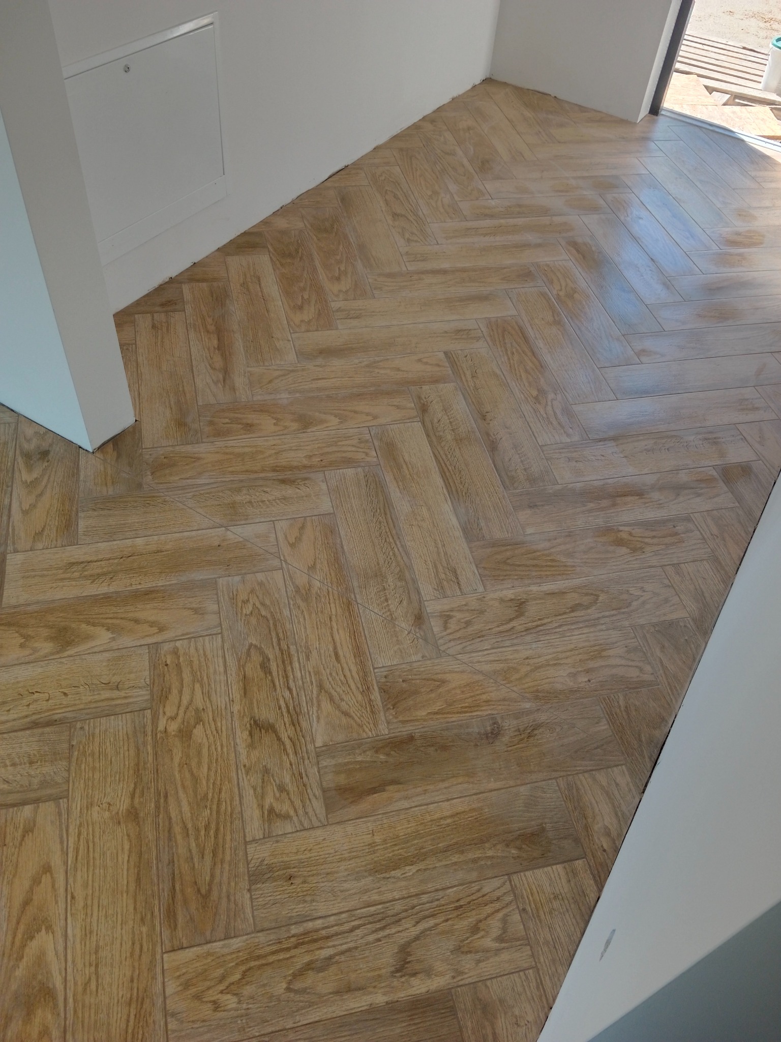 Ułożona w jodełkę podłoga z płytek imitujących drewno, widok z góry, jasne wnętrze.