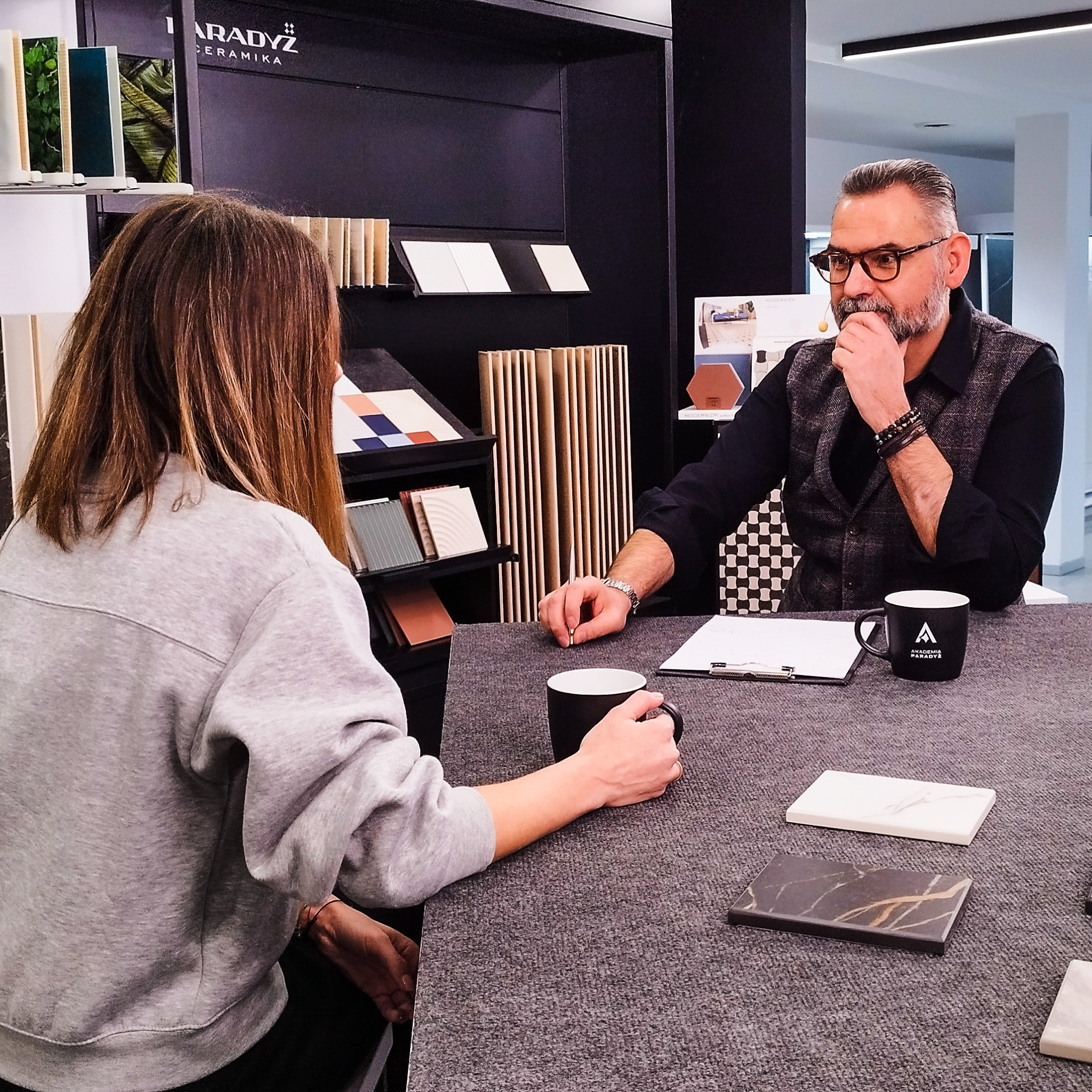 Konsultacja klienta z projektantem wnętrz w salonie płytek ceramicznych w Przeworsku, prezentacja próbek płytek na stole.