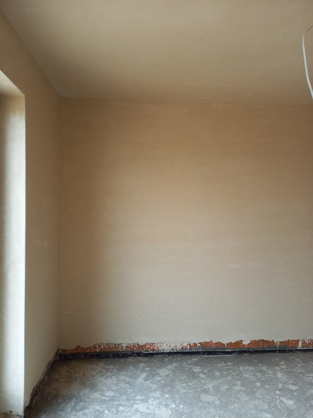 Pokój po nałożeniu gładzi, widoczne ślady na podłodze i dolnej części ścian, przygotowany do dalszych prac wykończeniowych.