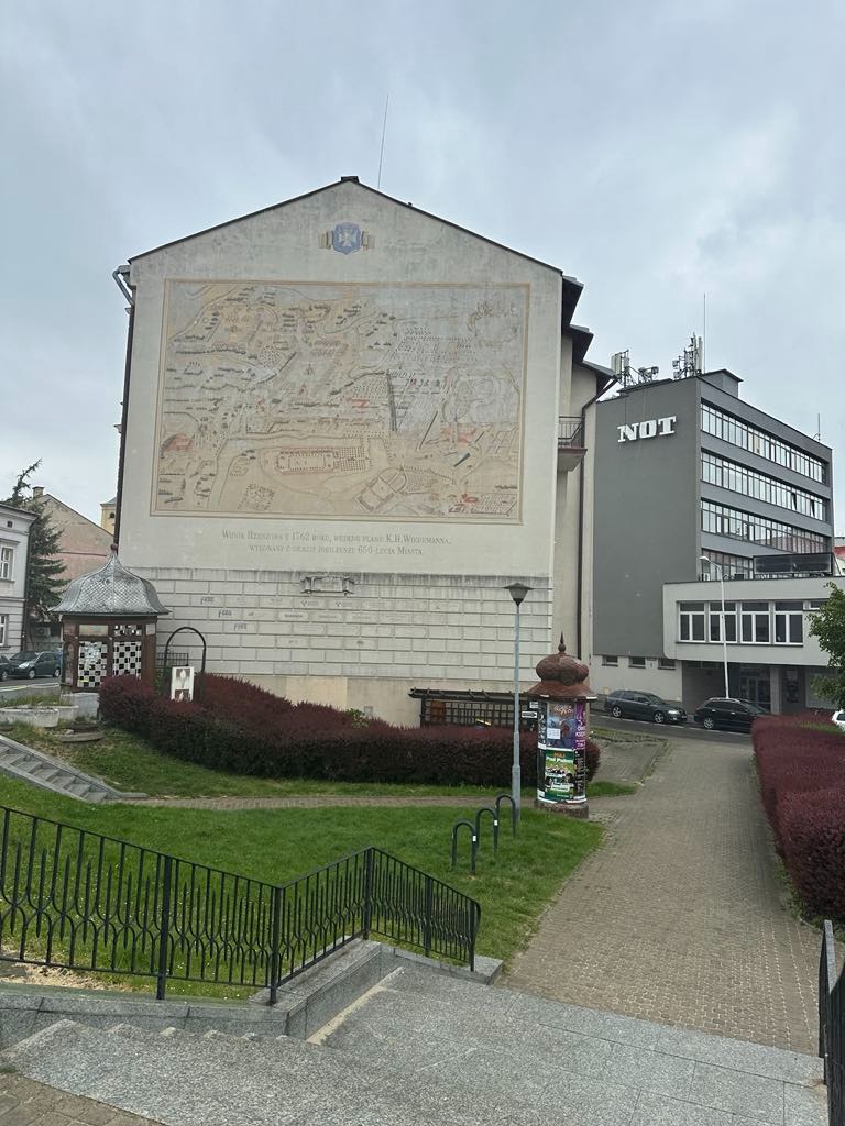 Budynek z muralem przedstawiającym plan Rzeszowa z 1762 roku, wykonany na 650-lecie miasta. Widok z dołu, schody prowadzą do budynku.