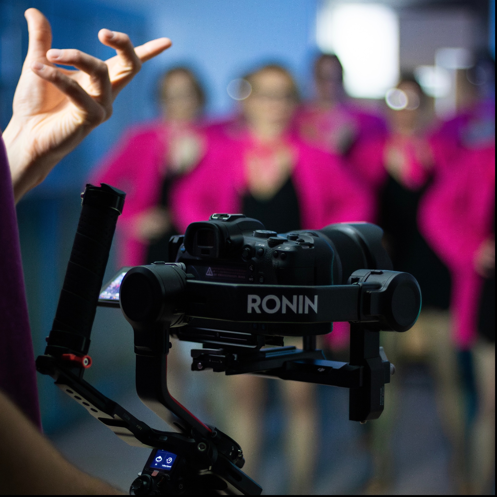 Kamera Ronin na gimbalu podczas filmowania grupy kobiet w różowych marynarkach w Białej Podlaskiej, widoczna dłoń operatora.