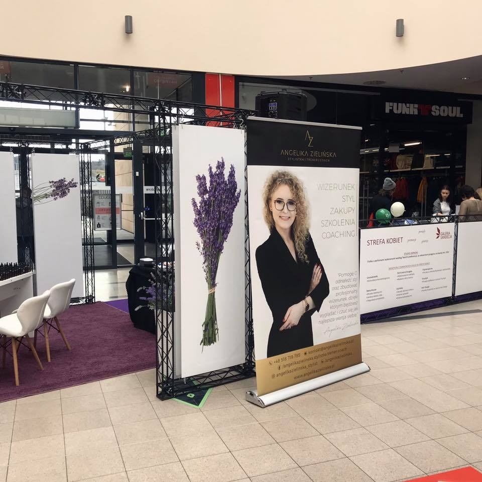 Stoisko z banerami reklamowymi w centrum handlowym, prezentujące ofertę wizerunkową, stylizacyjną i coachingową Angeliki Zielińskiej, z motywem lawendy.