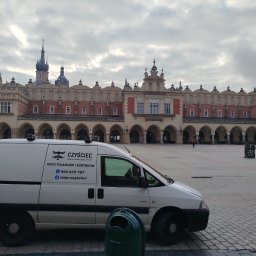 Szop Czyściec Karolina Markiewicz - Usługa mycia pojazdów i budynków: biały van firmy 'Czyściec' na tle Sukiennic w Krakowie. Napis na samochodzie: 'Mycie pojazdów i budynków'.
