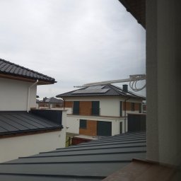 SYSCON - Widok z okna na dom z panelami słonecznymi na dachu i przewodem wentylacyjnym, prawdopodobnie w trakcie montażu.