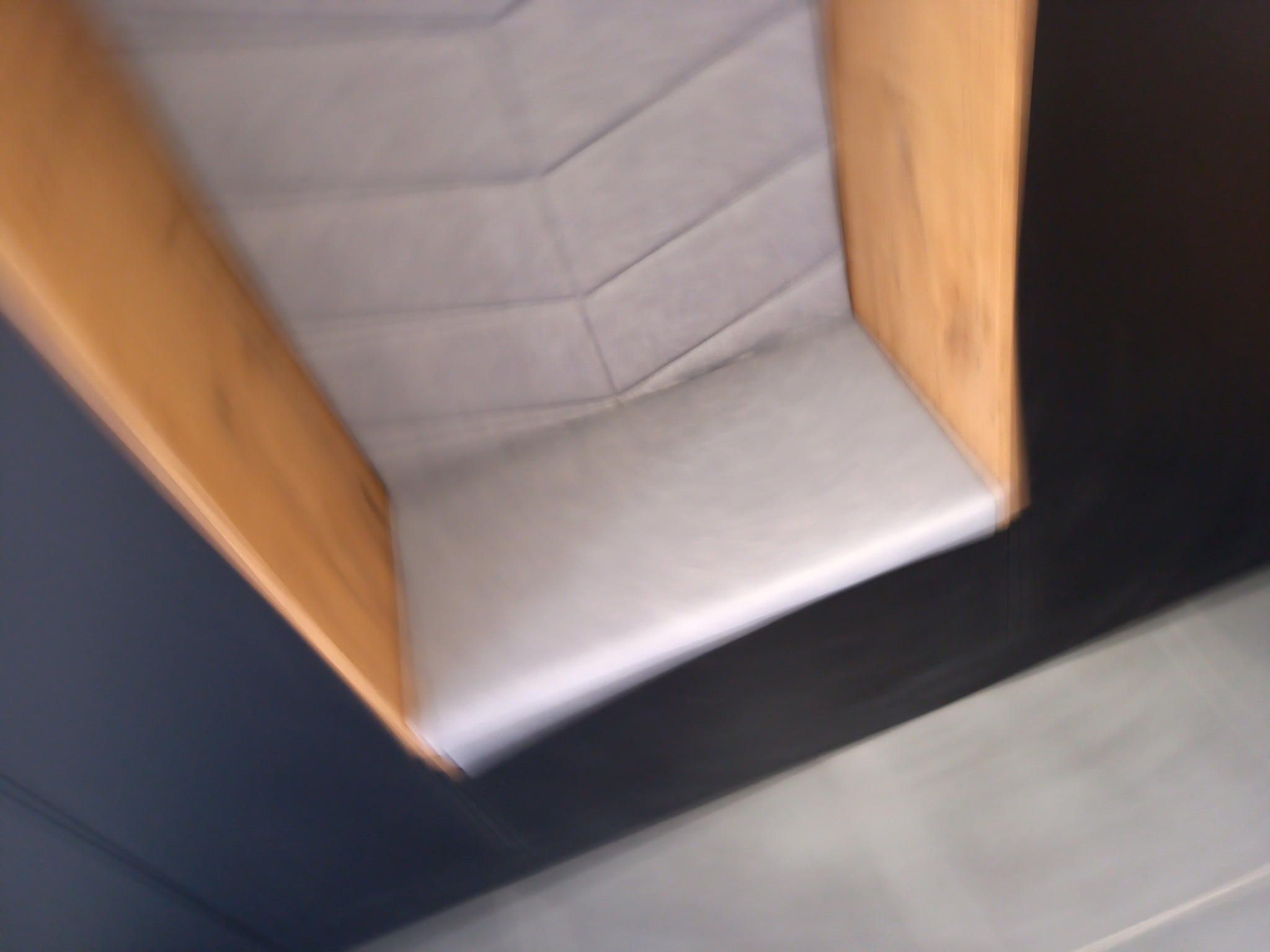 Wnętrze szafki z drewnianą ramą i tapicerowanym siedziskiem, widok od dołu pod kątem.