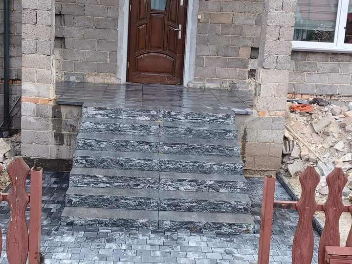 Ułożone schody z kostki granitowej prowadzące do wejścia domu w Częstochowie, widoczne ślady prac budowlanych w otoczeniu.