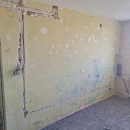 Przedsiębiorstwo Usługowe Jarosław Butowski - Ściana w trakcie remontu z odkrytymi przewodami elektrycznymi w bruzdach, widoczne ślady po starych instalacjach i przygotowanie do dalszych prac wykończeniowych.
