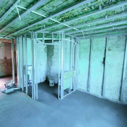 Przedsiębiorstwo Usługowe Jarosław Butowski - Stelaż z profili stalowych tworzący konstrukcję ścian działowych w pomieszczeniu w trakcie prac wykończeniowych, widoczne instalacje pod sufitem, narzędzia w skrzynce po lewej.