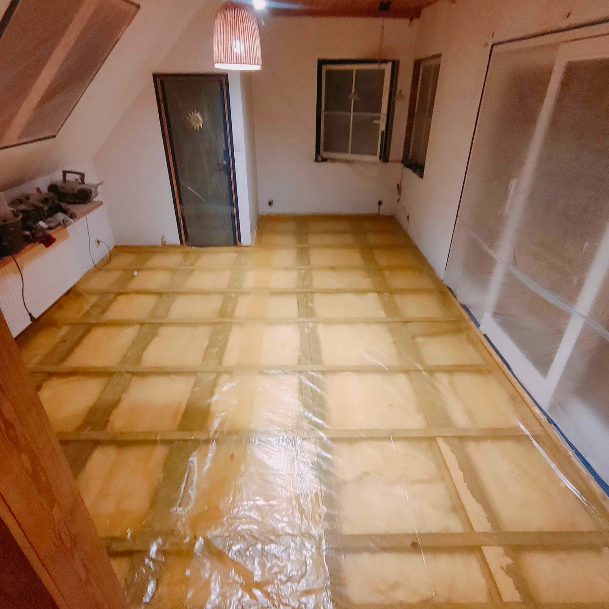 Podłoga w trakcie przygotowania do dalszych prac w Banino, zabezpieczona folią ochronną, widoczne drewniane legary i ocieplenie.