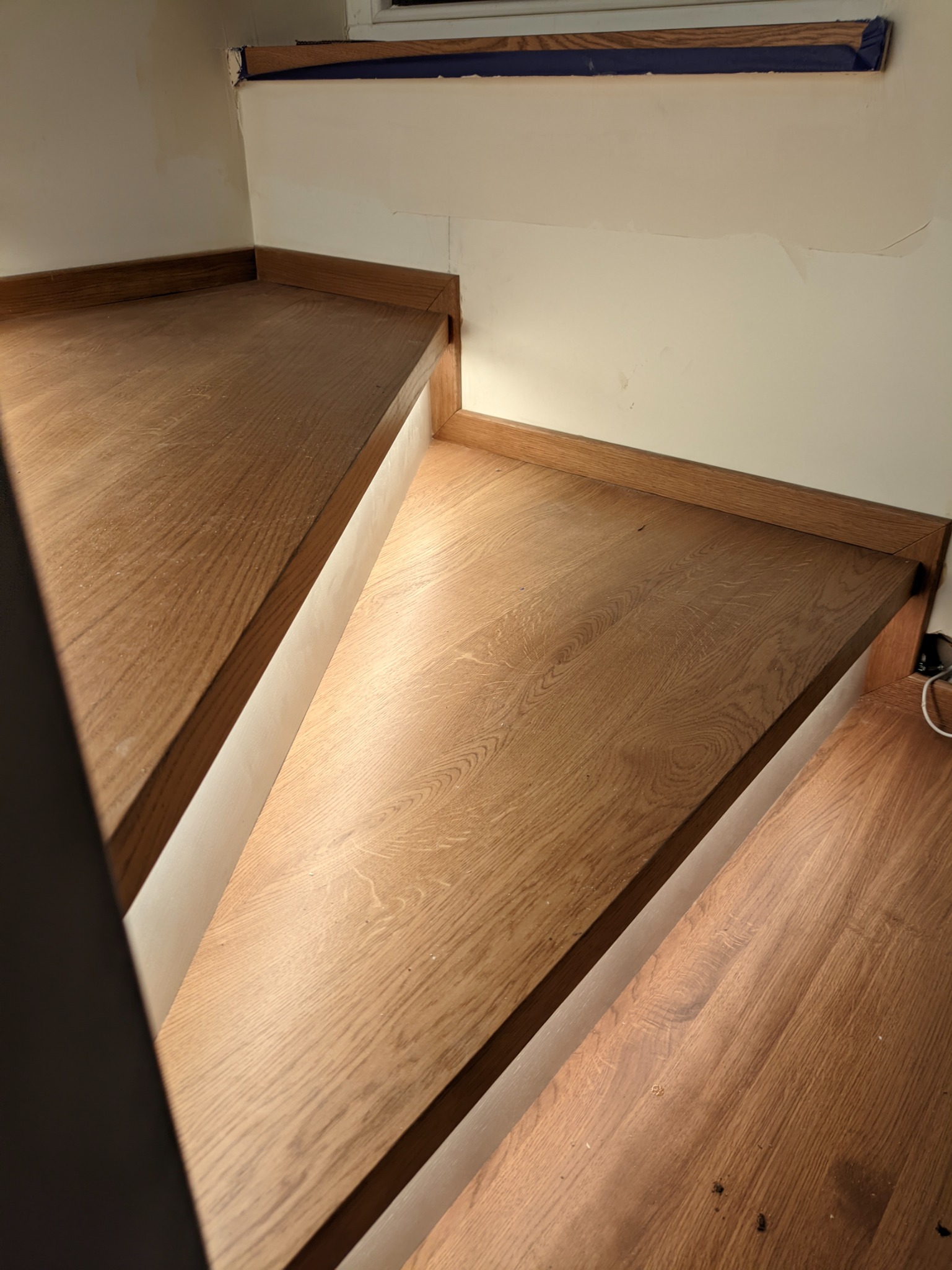 Drewniane schody z oświetleniem LED, widok z dołu, ukazujący strukturę drewna i minimalistyczne wykończenie.