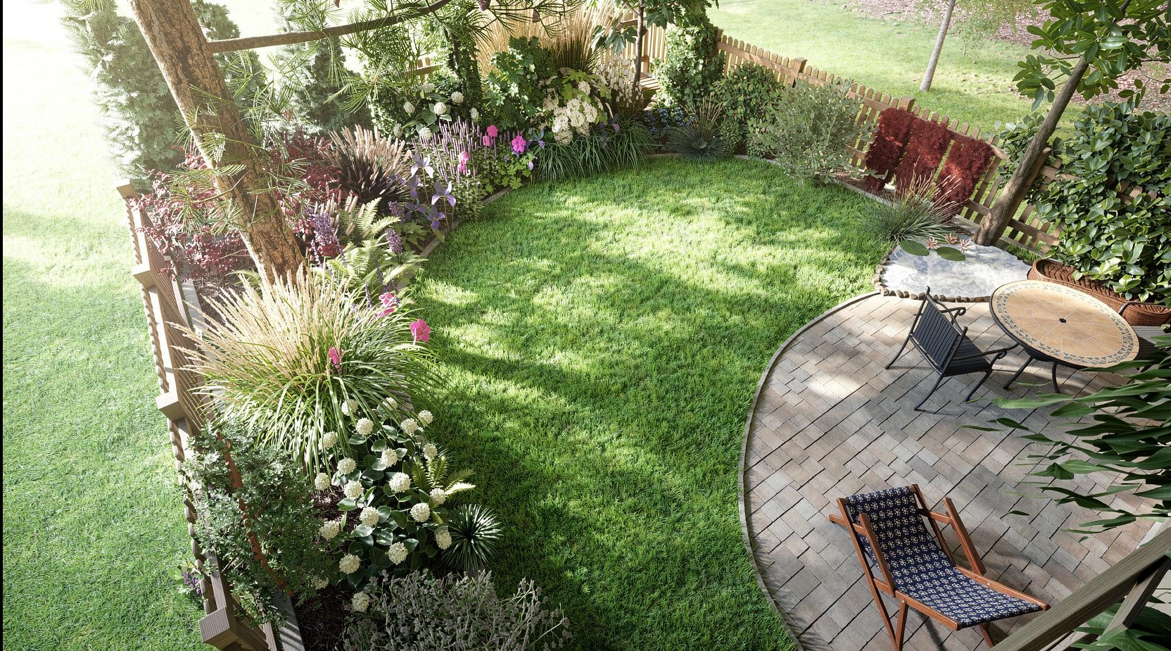 Widok z góry na zadbany ogród z trawnikiem, rabatami kwiatowymi i drewnianym tarasem z meblami ogrodowymi. Uwagę przyciąga bujna roślinność i harmonijna kompozycja.