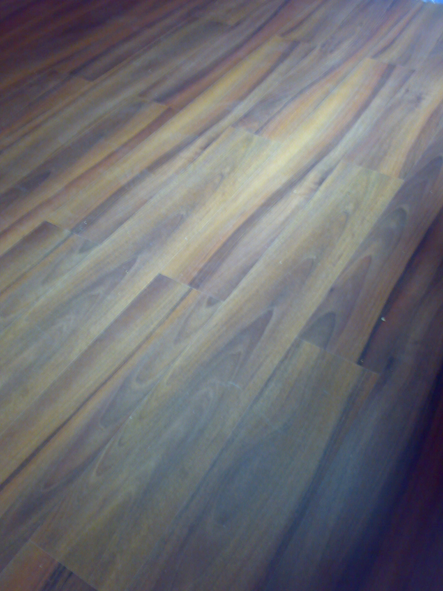 Ułożone deski podłogowe z widocznym usłojeniem, sfotografowane pod kątem, z efektem rozmycia.