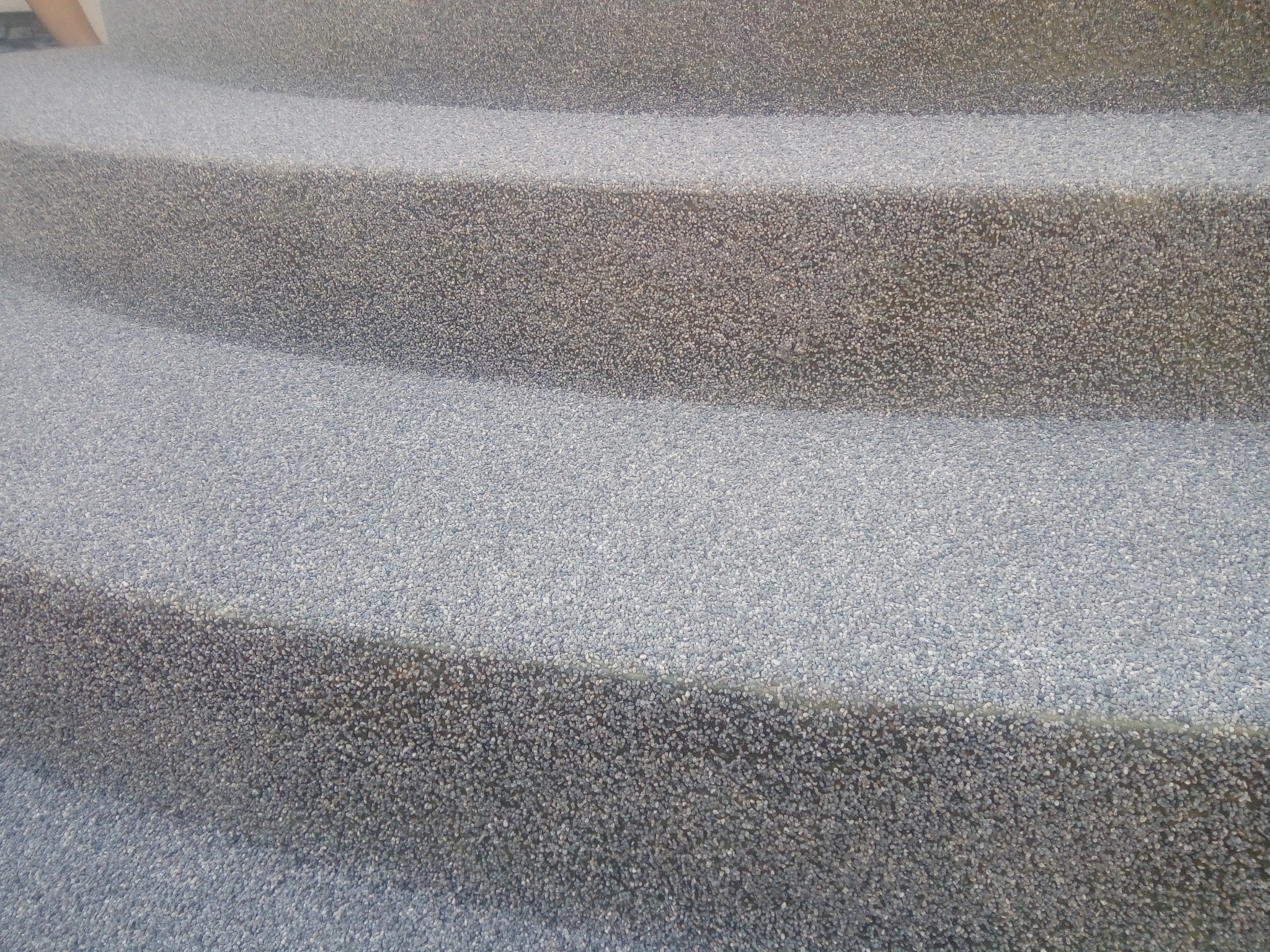 Schody zewnętrzne pokryte szarą posadzką żywiczną z drobnym kruszywem, widok z bliska na fakturę powierzchni.