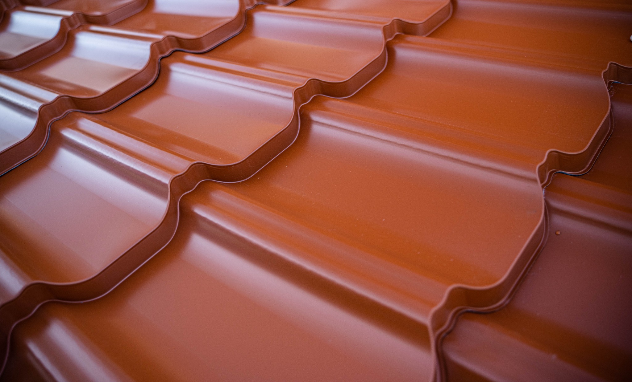 Błyszczące, brązowe dachówki ceramiczne ułożone w regularny wzór, widok z bliska, podkreślone światłem odbijającym się od powierzchni.