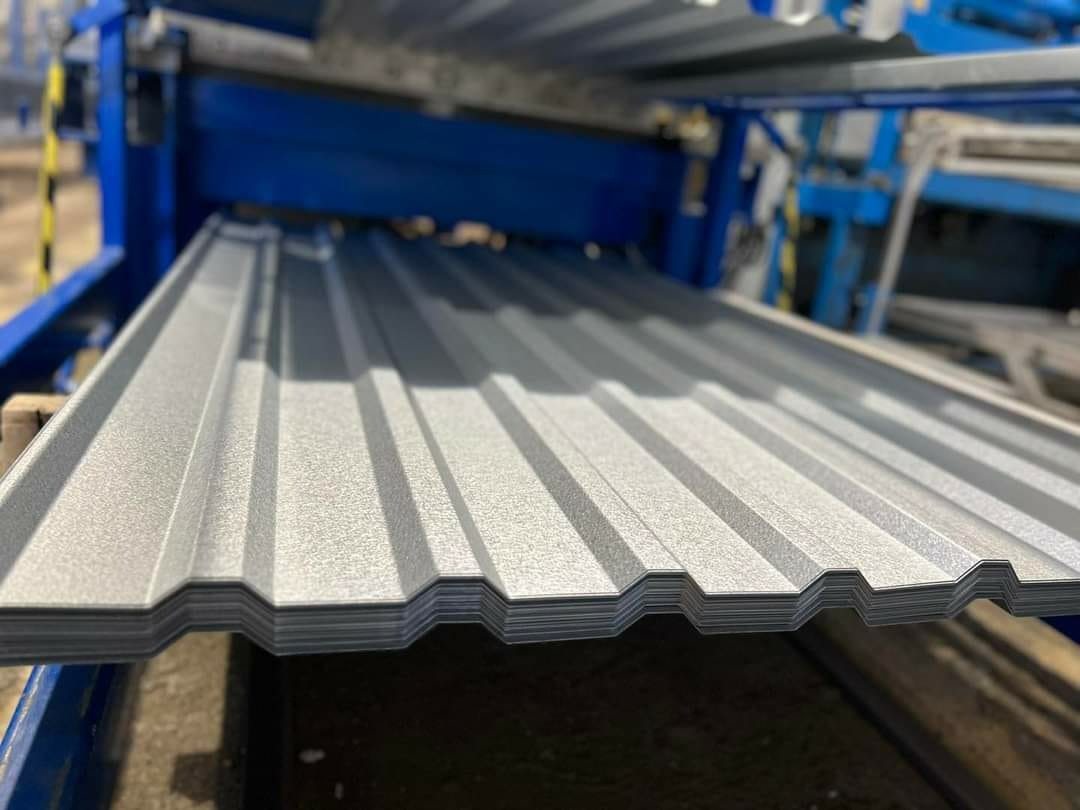 Proces produkcji szarej blachy profilowanej w Lubinie, widoczna maszyna formująca z niebieskimi elementami.