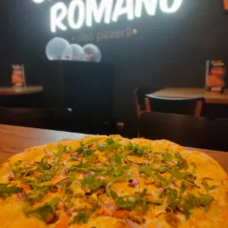 Pizza z owocami morza i rukolą na drewnianym stole, w tle neonowy szyld pizzerii Speedy Romano i dekoracyjne balony.