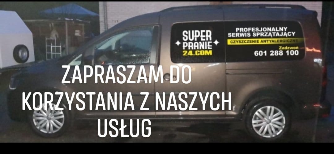 Brązowy samochód dostawczy z naklejką reklamową firmy oferującej usługi sprzątające i prania, w tle widoczny biały przyczepka i namiot.