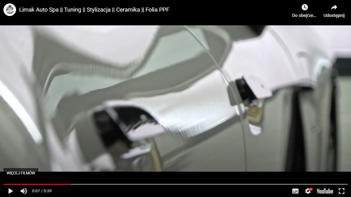 Błyszcząca, srebrna karoseria samochodu po zabiegu detailingu, z widocznymi refleksami światła i fragmentem klamki.