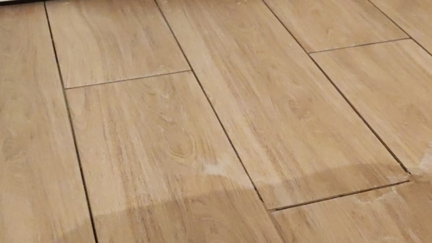 Jasne panele podłogowe ułożone wzdłużnie, widoczne delikatne słoje drewna i wąskie fugi.