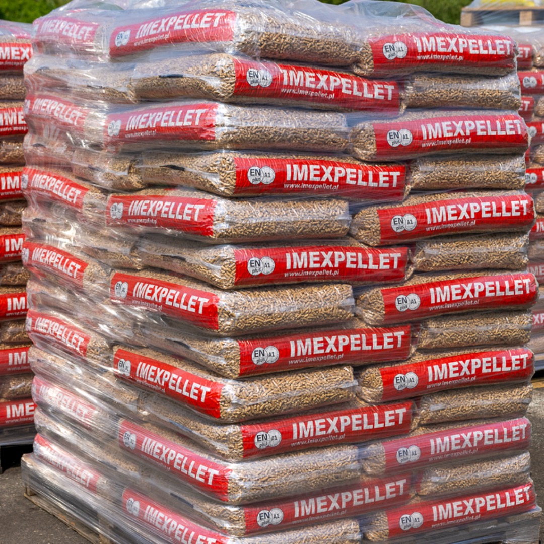 Stos worków z pelletem drzewnym marki Imexpellet, ułożonych na palecie i owiniętych folią, z widocznym oznaczeniem EN A1 plus.