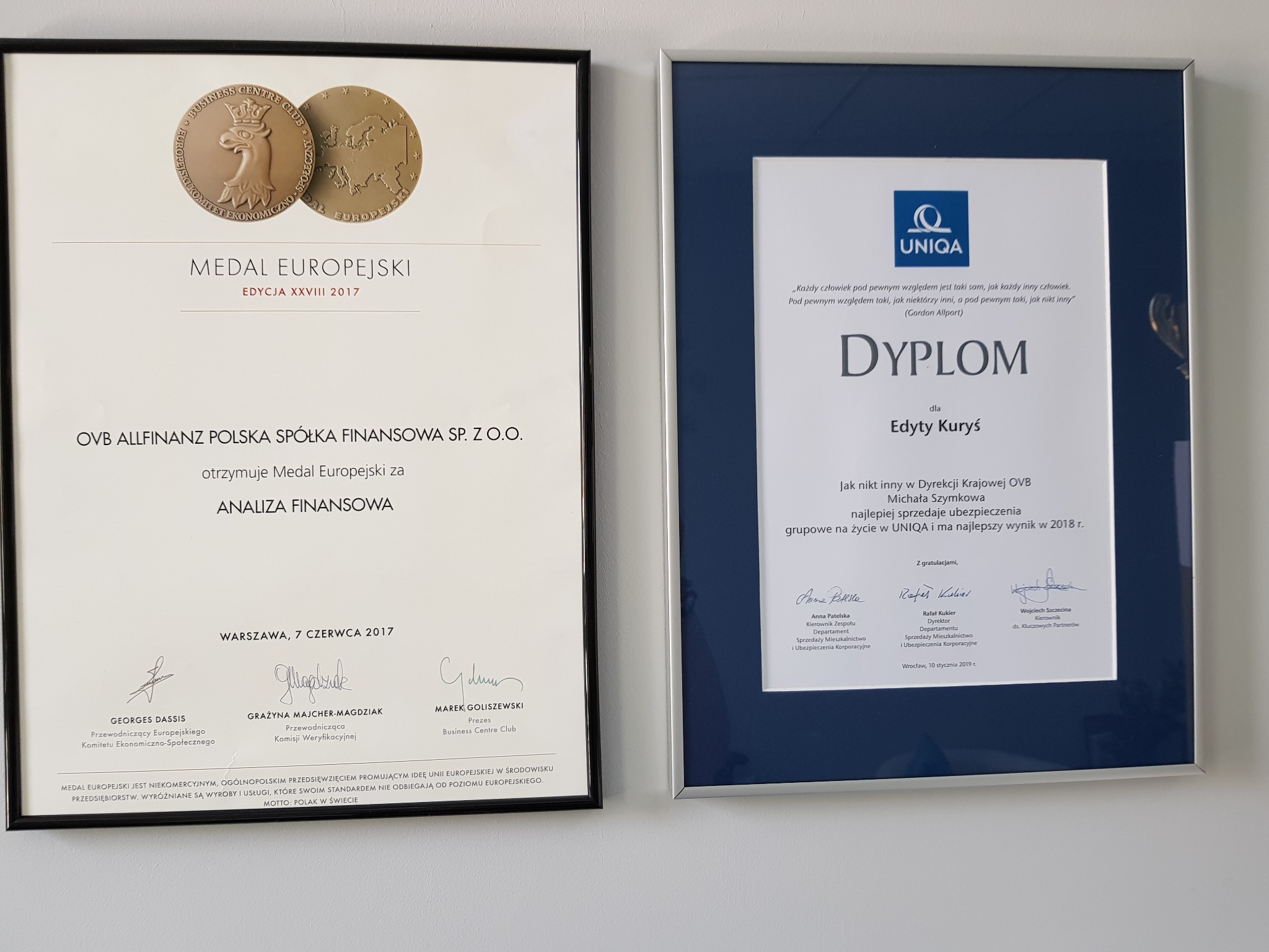 Dwa oprawione dokumenty wiszące na ścianie: Medal Europejski za analizę finansową dla OVB Allfinanz Polska Spółka Finansowa Sp. z o.o. oraz dyplom od UNIQA dla Edyty Kuryś za najlepszą sprzedaż...