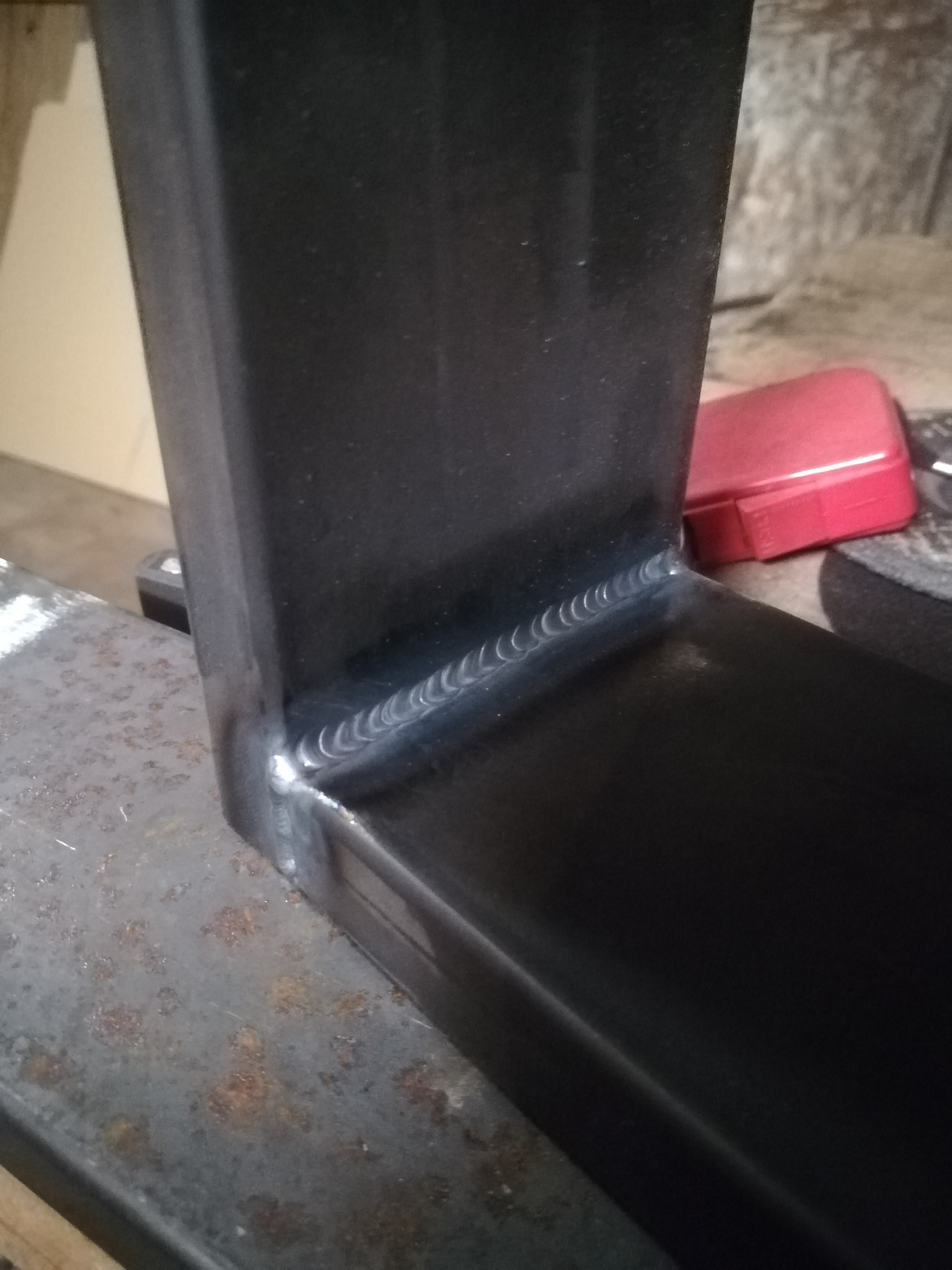 Spoina na profilu stalowym, wykonana w Rybniku, widoczna na tle zardzewiałego stołu warsztatowego.