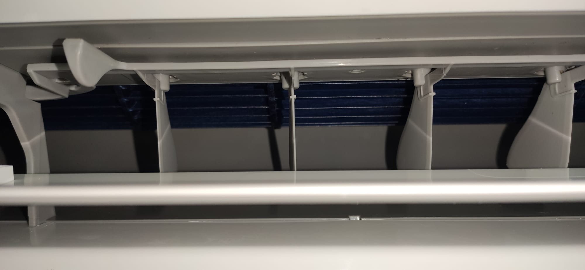 Wnętrze klimatyzatora z widocznymi żaluzjami regulującymi przepływ powietrza, widok z dołu.