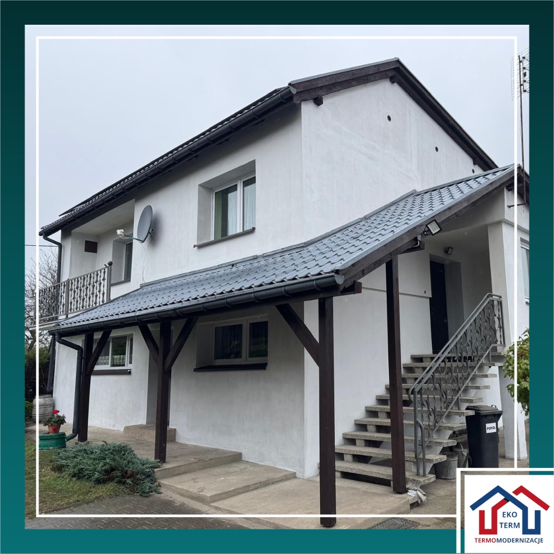 Ocieplona elewacja domu w Łodzi, przygotowana pod tynk. Widoczny styropian grafitowy 15 cm i barwiony grunt. Elewacja w kolorze białym.