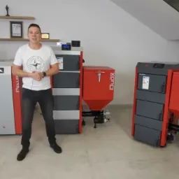 Prezentacja różnych modeli kotłów na paliwo stałe: Pello, Duox i Eco Matix, z mężczyzną w białej koszulce stojącym przed nimi.