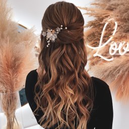 Oliwia Konopka - Uczesanie z podpiętymi włosami, ozdobione delikatną spinką z kwiatami i perłami, na tle dekoracji z pampasów i neonowego napisu.