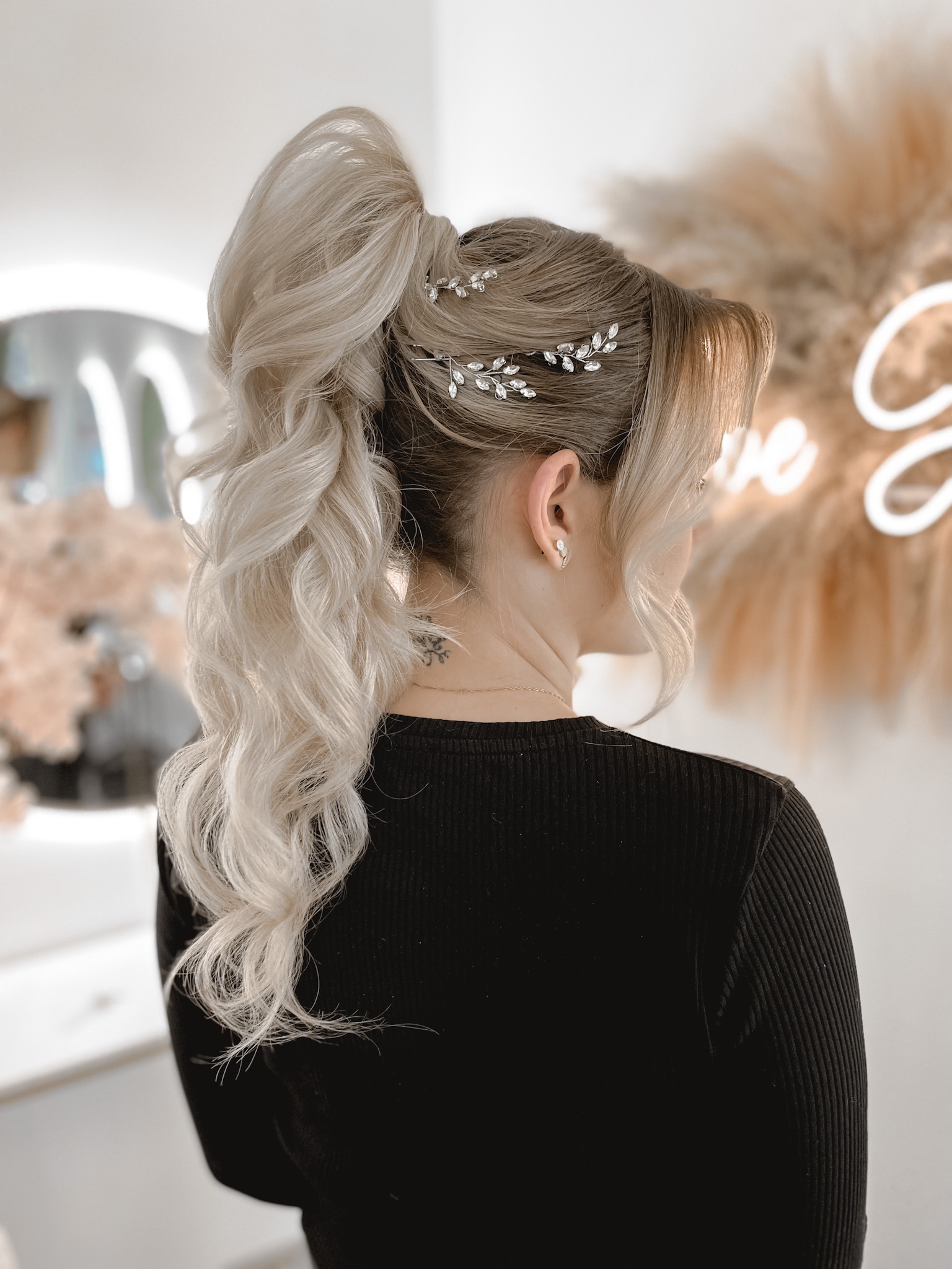 Upięty blond kucyk z ozdobnymi spinkami w kształcie gałązek, widok z tyłu, tatuaż na karku.