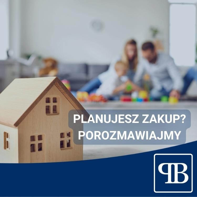 Drewniany model domu na pierwszym planie, w tle rozmyta rodzina z dzieckiem bawiąca się klockami w salonie. Widoczny napis 'Planujesz zakup? Porozmawiajmy' oraz logo firmy.