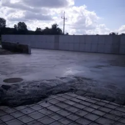 Wylewka betonowa w trakcie prac, widoczna siatka zbrojeniowa i świeży beton na tle betonowego muru.