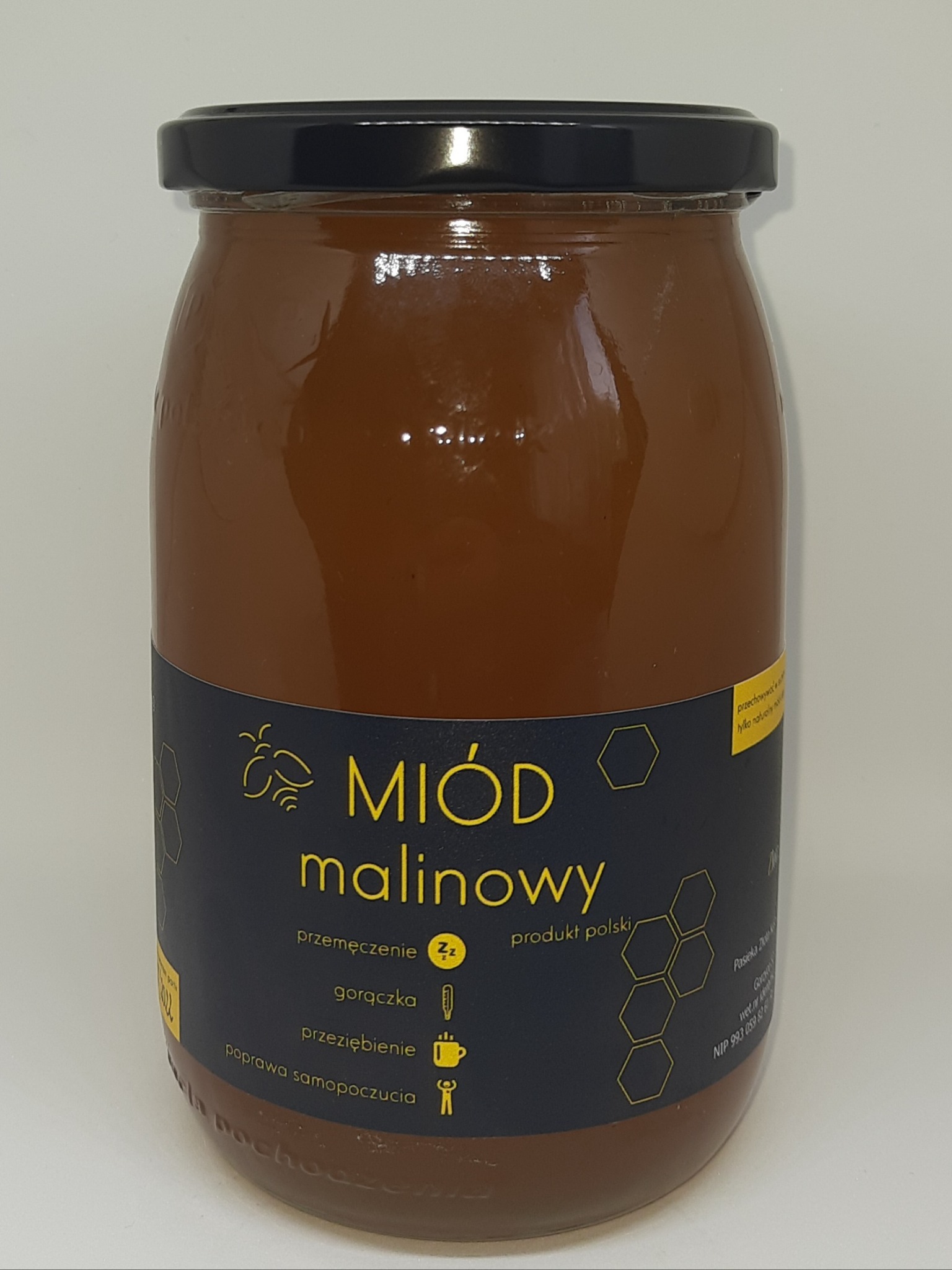 Słoik z ciemnym miodem malinowym, etykieta z informacjami o właściwościach i pochodzeniu produktu, czarne wieczko.