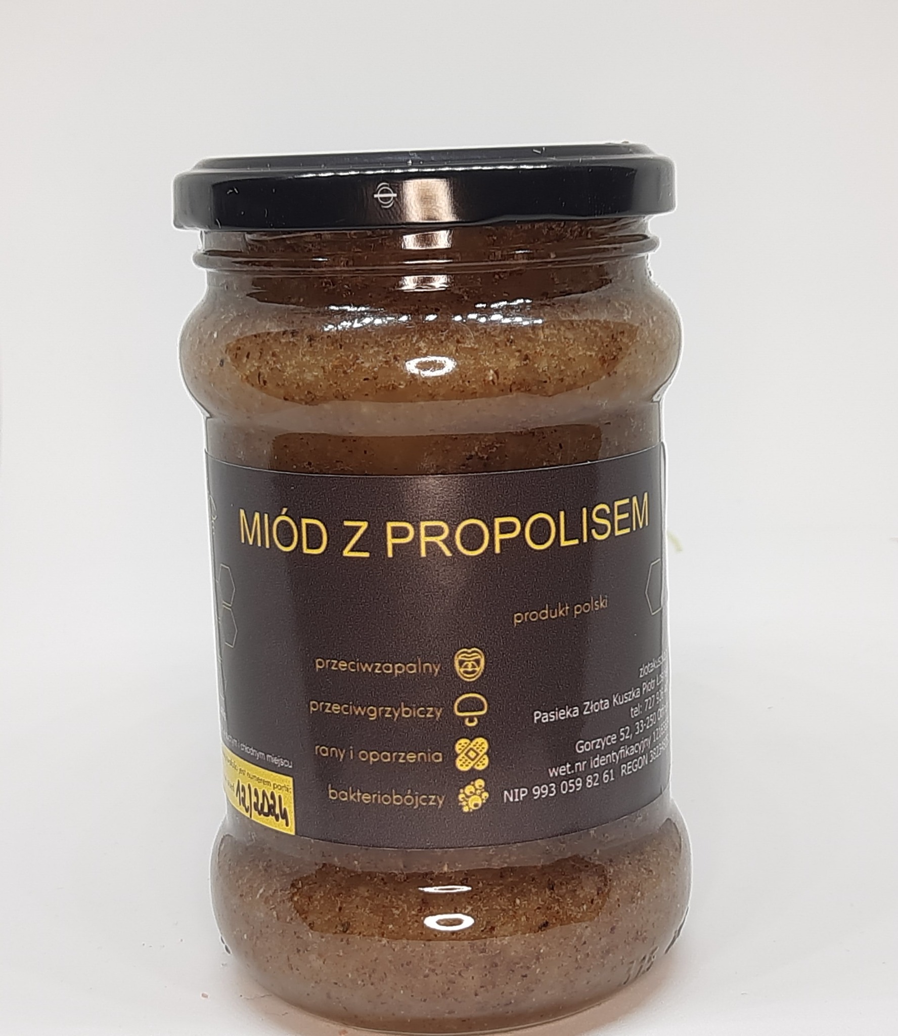 Słoik z miodem z propolisem, etykieta z informacjami o produkcie i właściwościach leczniczych, czarna zakrętka, produkt polski.