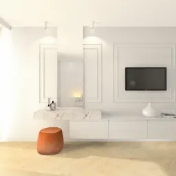 Minimalistyczna, jasna toaletka z marmurowym blatem, okrągłym pomarańczowym siedziskiem i telewizorem na ścianie w ramie.