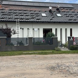 Avoltaic Kamil Kopaniecki - Montaż paneli fotowoltaicznych na dachu domu w Dębnie. Dwóch monterów w trakcie pracy, panele ułożone częściowo, widoczne okna dachowe i drabiny.