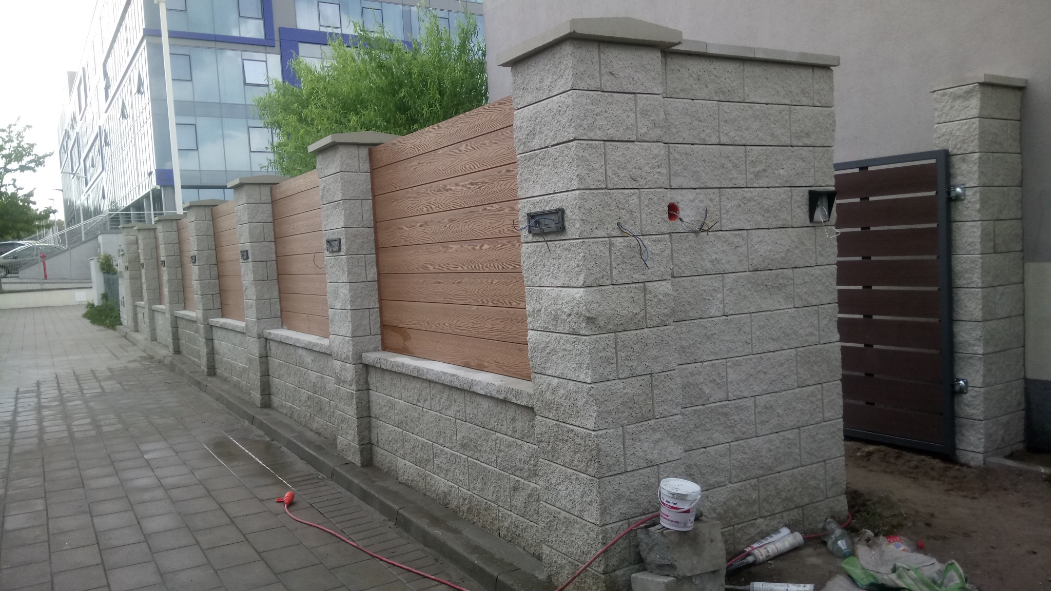 Nowoczesne ogrodzenie panelowe z elementami betonowymi w Łomży, widoczne przewody elektryczne, prawdopodobnie przygotowane pod oświetlenie.