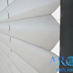 Detal białej, plisowanej osłony okiennej z widocznym logo firmy na pierwszym planie.