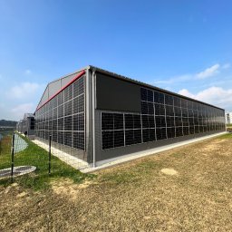 F.H.U LED ELEKTRO - Duży budynek przemysłowy pokryty panelami słonecznymi, widok z zewnątrz w słoneczny dzień.