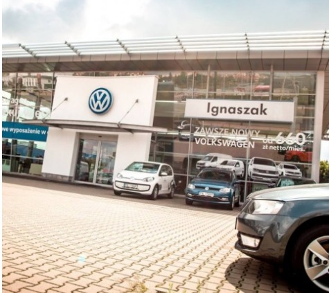 Salon samochodowy marki Volkswagen z widocznymi modelami aut na zewnątrz i ekspozycją wewnątrz budynku.