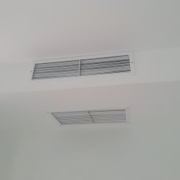 Klimaver - Dwa białe, prostokątne nawiewniki wentylacyjne zamontowane w białym suficie, jeden podłużny, drugi kwadratowy.