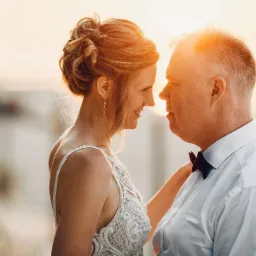 Para wpatrzona w siebie podczas zachodu słońca, kobieta w koronkowej sukni, mężczyzna w białej koszuli i muszce