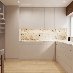 Beżowa kuchnia z marmurowym blatem i backsplashiem, złota bateria, oświetlenie LED podszafkowe, drewniana podłoga i schody spiralne w tle.