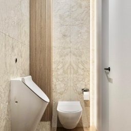 PROJEKTORNIA.COM.PL - Nowoczesna łazienka z wiszącą toaletą i bidetem, marmurowe płytki na ścianach, drewniane panele dekoracyjne, podświetlenie LED wzdłuż ściany, jasna drewniana podłoga.