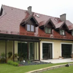 Elewacja domu jednorodzinnego z czerwoną dachówką i przeszkloną werandą. Widoczny zadbany trawnik i elementy architektury ogrodowej. Ujęcie w pochmurny dzień.